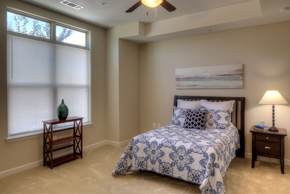 A cozy bedroom with a neatly made bed and a window allowing natural light.