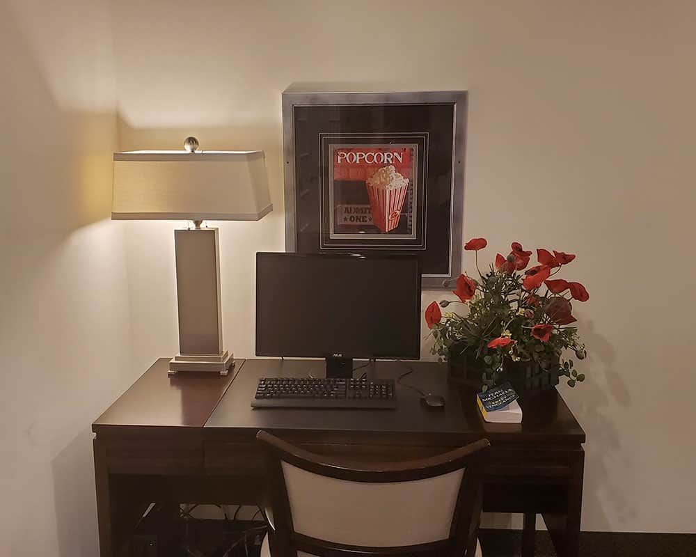 A cozy home workspace setup with a computer, lamp, and decorative flowers.
