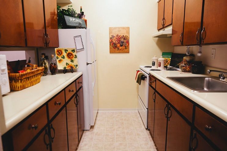 A cozy kitchen with wooden cabinets, a fridge, and an oven, decorated with floral accents.