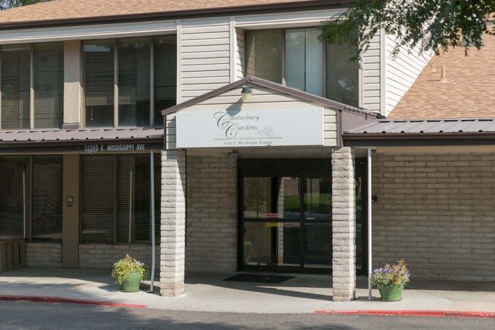 A building entrance with an awning and potted plants on either side.