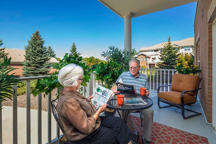 A senior couple enjoying coffee and reading on a porch.