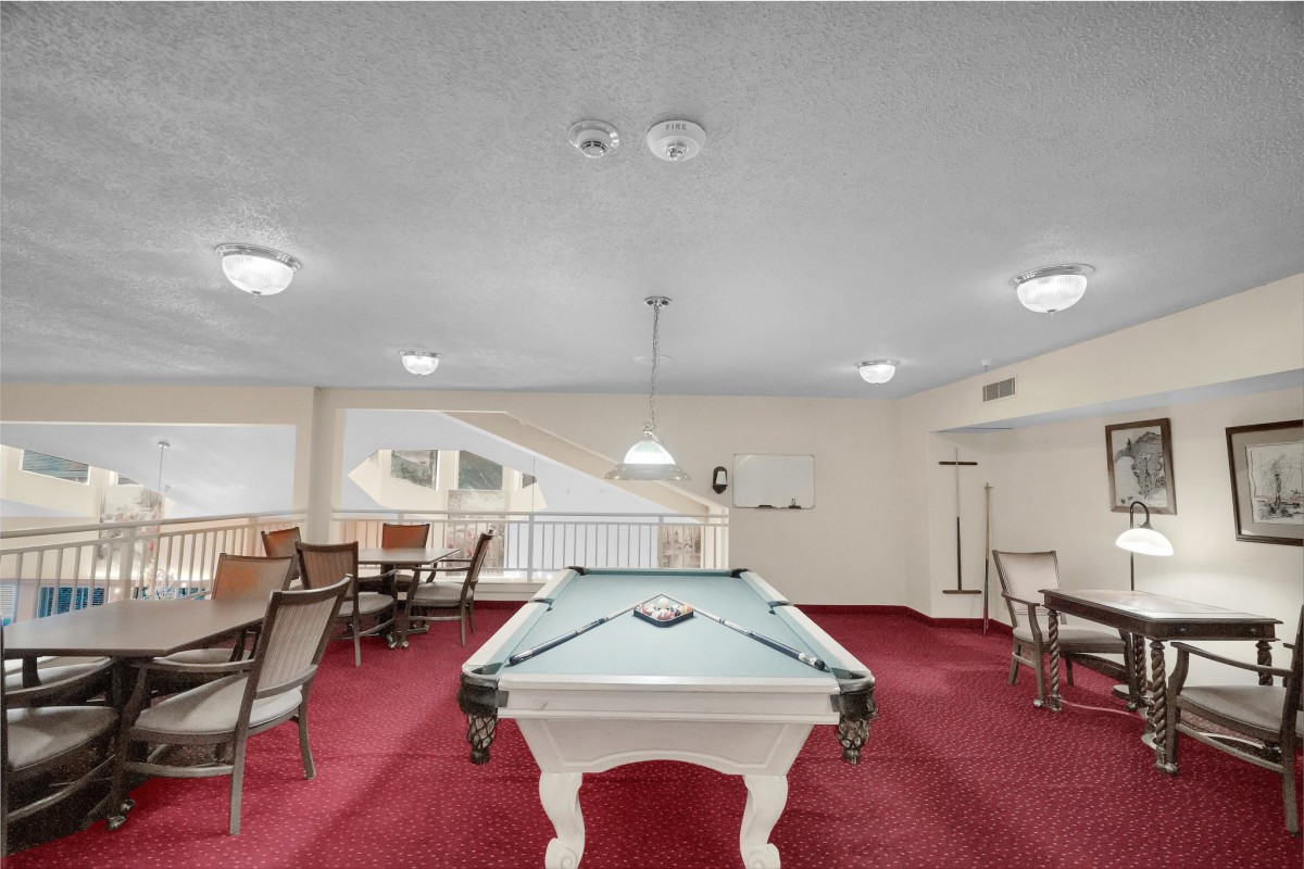 Spacious game room featuring a pool table and elegant red carpeting.