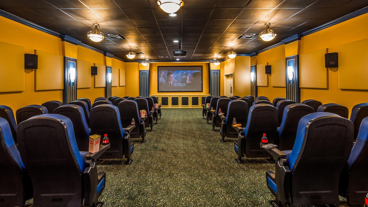 A cozy home theater setup with rows of seats facing a large projector screen.