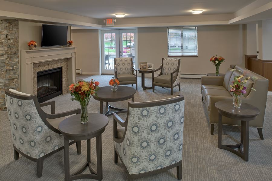 A cozy living room with comfortable chairs, small tables, and a fireplace.