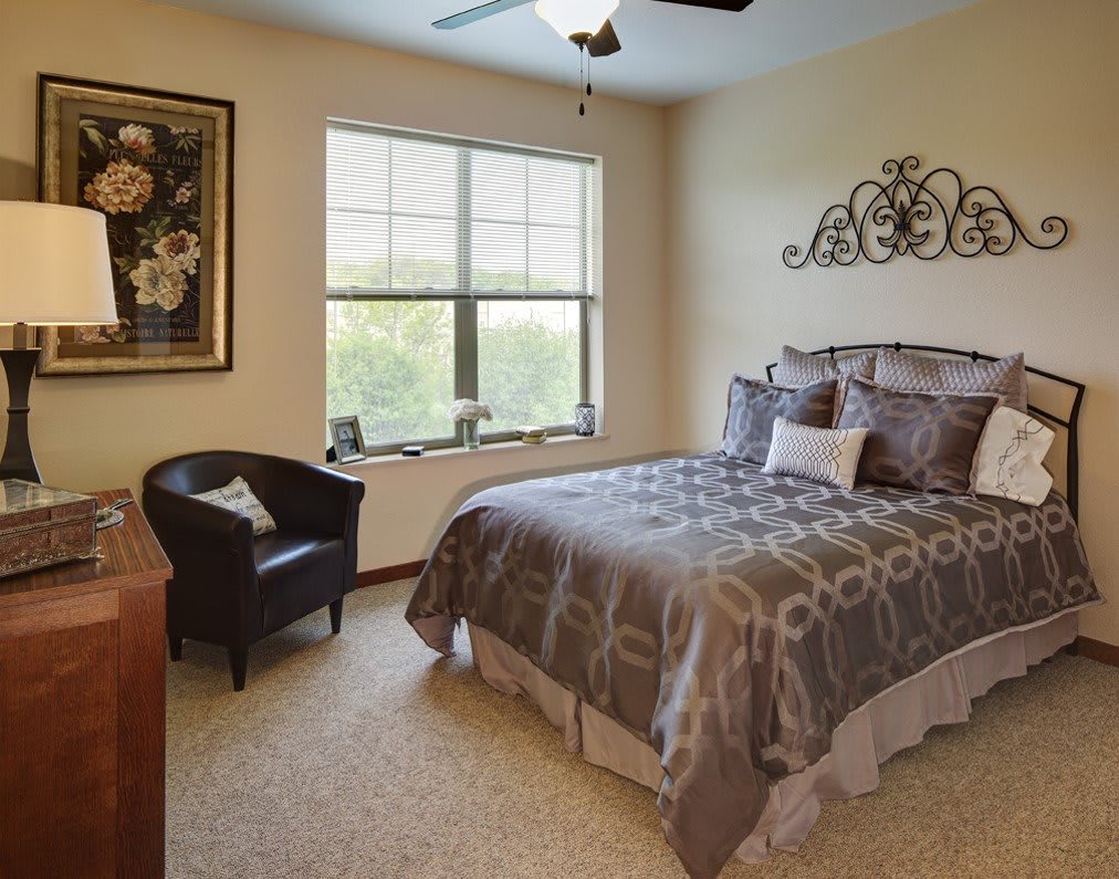 A cozy bedroom with a bed, armchair, and decorative wall art.