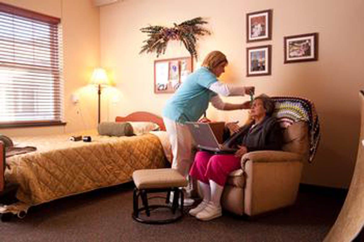 A caregiver assists an elderly person in a cozy living space.