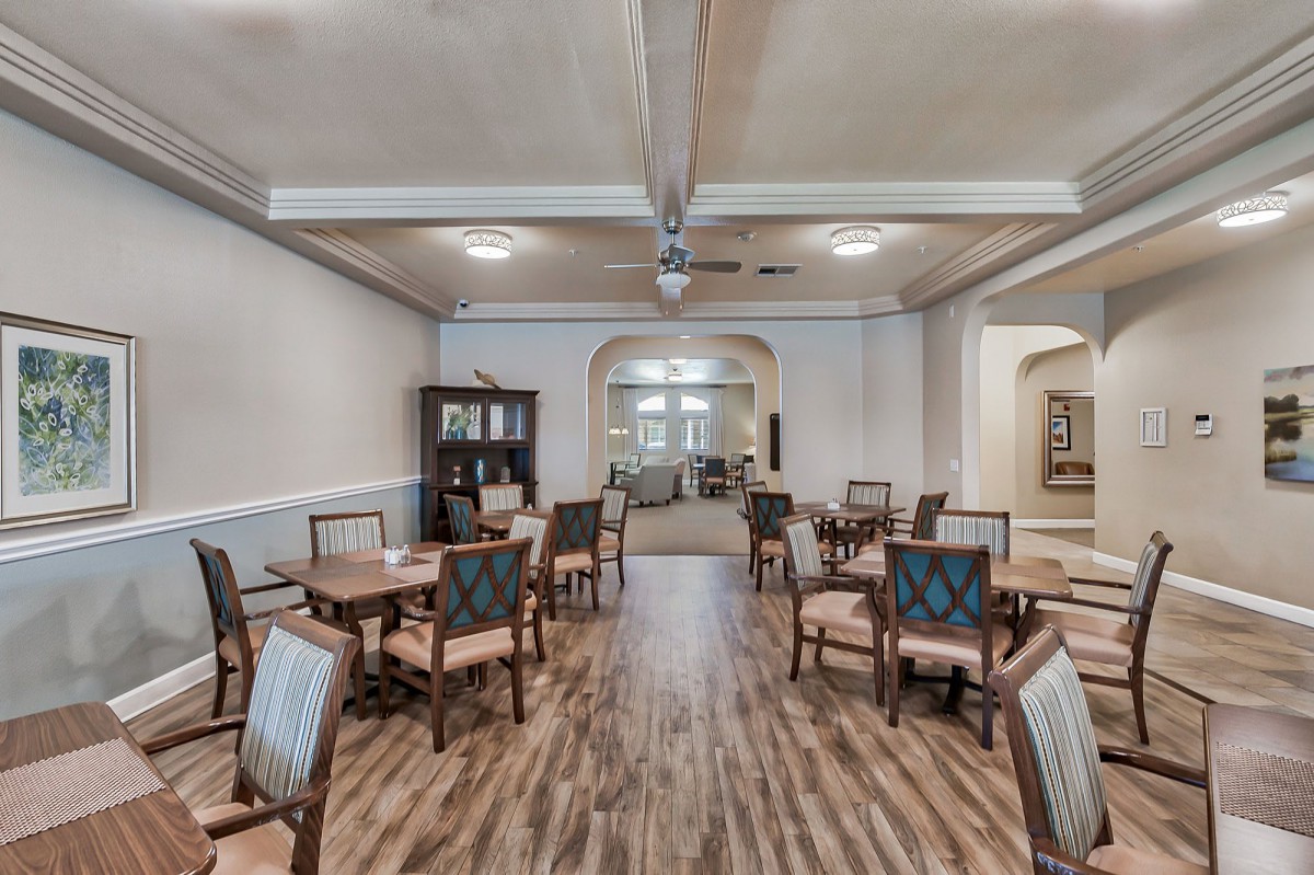 An elegant dining room with neatly arranged tables and chairs on a polished wooden floor.