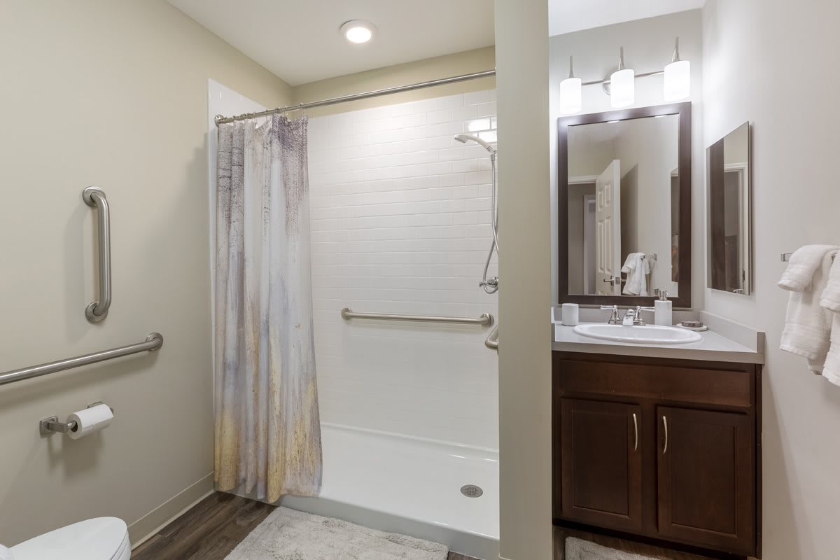 A modern bathroom with a shower area, vanity, and mirror.