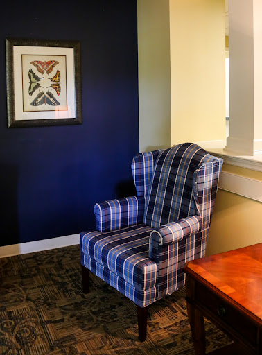 A cozy plaid armchair set against a dark blue wall, complemented by framed artwork.