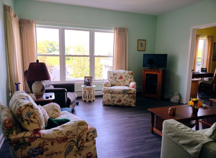A cozy living room with floral-patterned furniture and a large window.