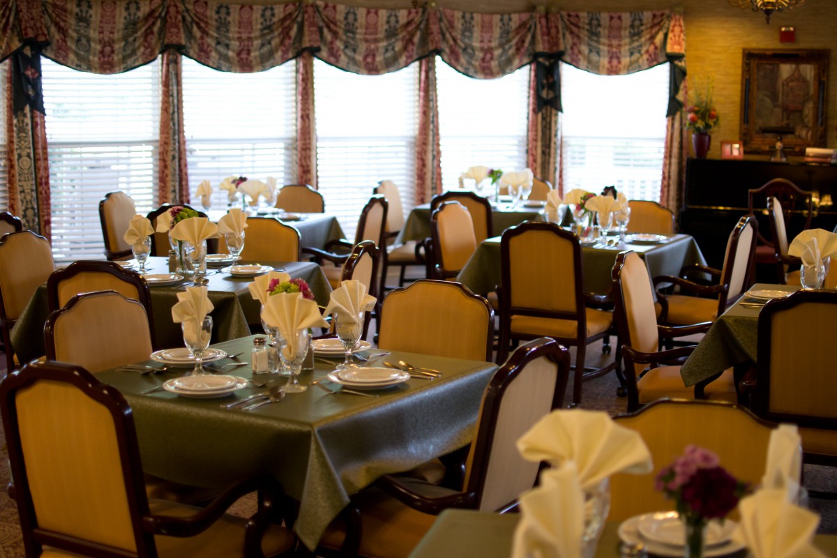 An elegant dining room with neatly arranged tables and chairs, complete with napkin settings.