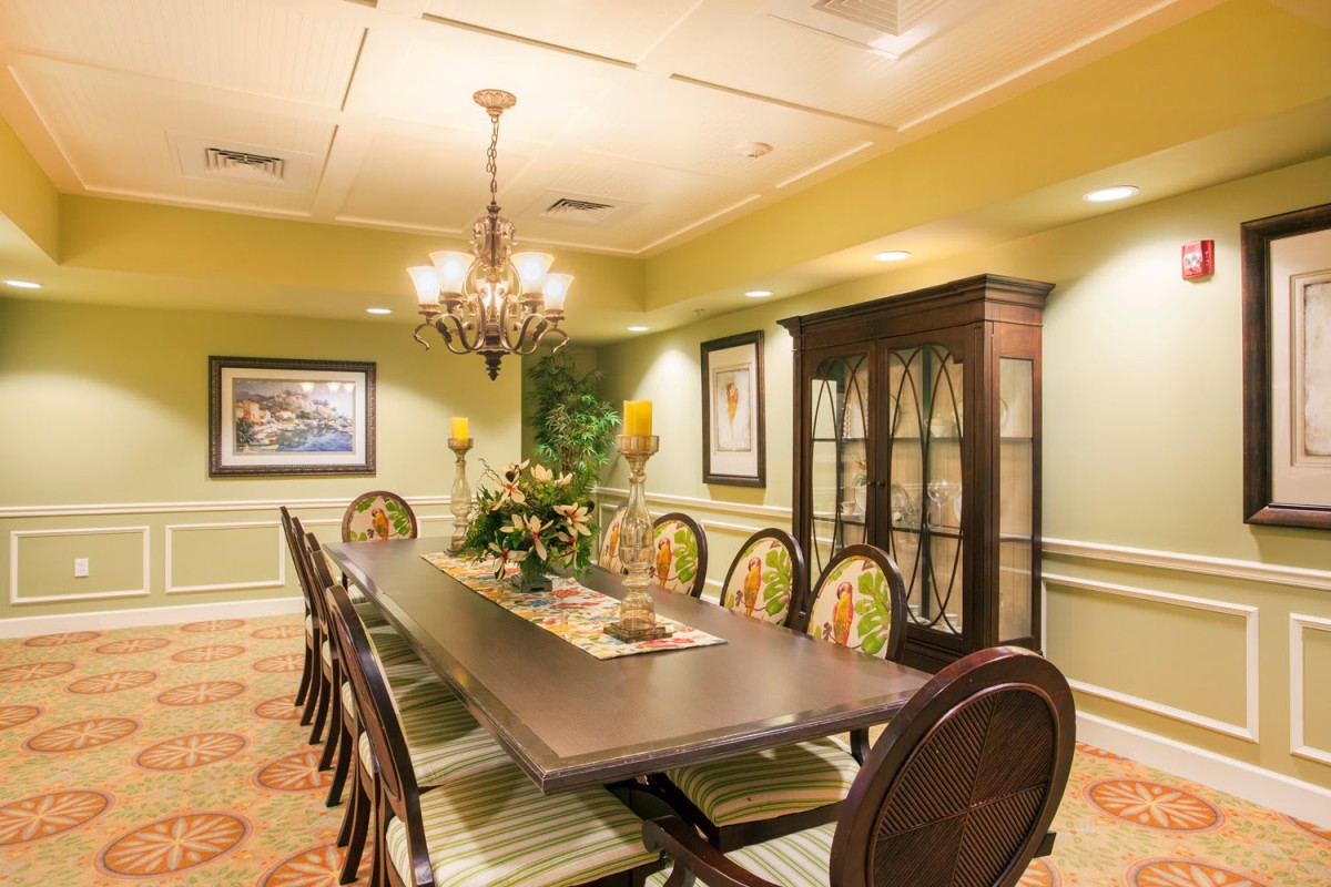 A well-decorated dining room with a long table, elegant chairs, and a chandelier.
