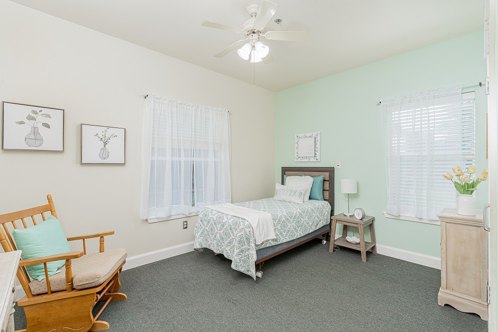 A cozy bedroom with a single bed, rocking chair, and neutral decor.