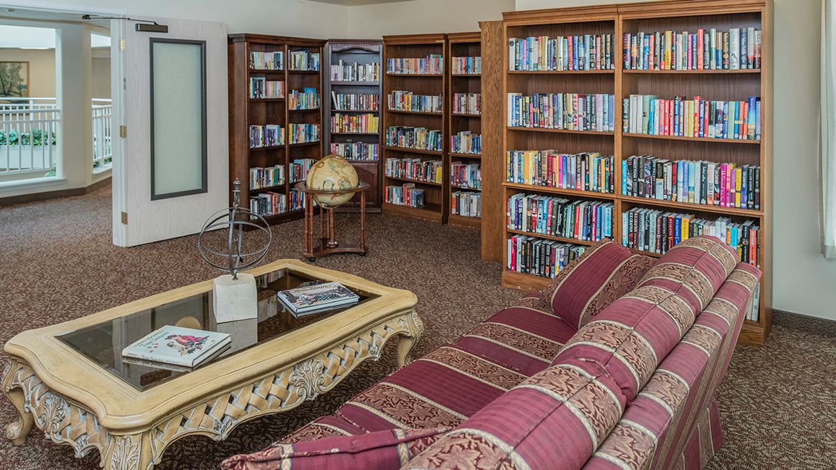 A cozy library with bookshelves, a globe, and a comfortable sofa.