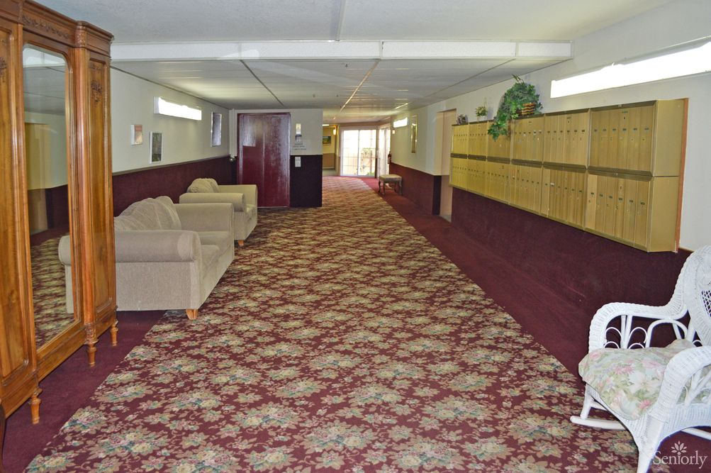 A hallway with patterned carpet, sofas, and lighting fixtures.