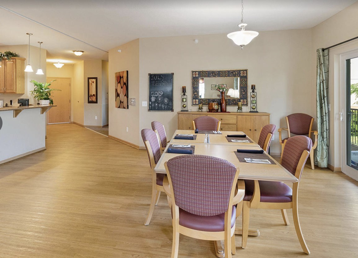 A modern dining room with a wooden table and chairs, featuring elegant lighting and decor.
