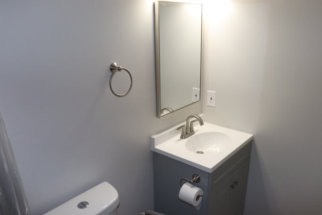 A minimalist bathroom with a sink, mirror, and toilet.