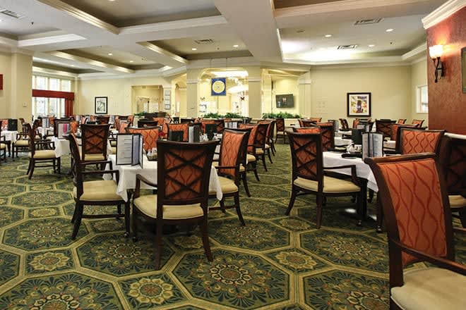 An elegantly designed dining area with neatly arranged tables and chairs, featuring a patterned carpet.