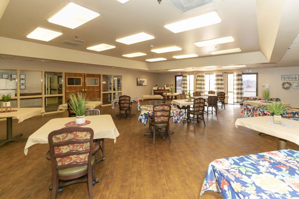 A spacious and well-lit dining area with multiple tables and chairs, featuring a warm interior design.