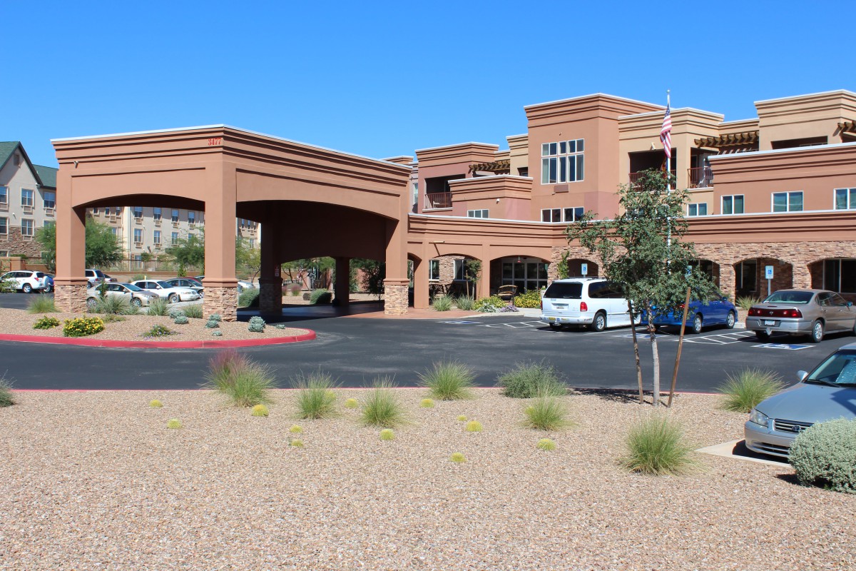A modern building with an entrance and a parking area in a desert landscape.