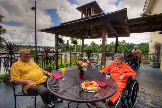 Two seniors enjoying a meal on an outdoor patio.