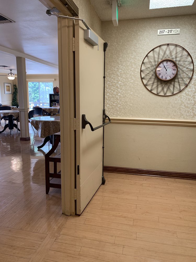 An open door in a hallway with a wall clock and visible furniture in the background.