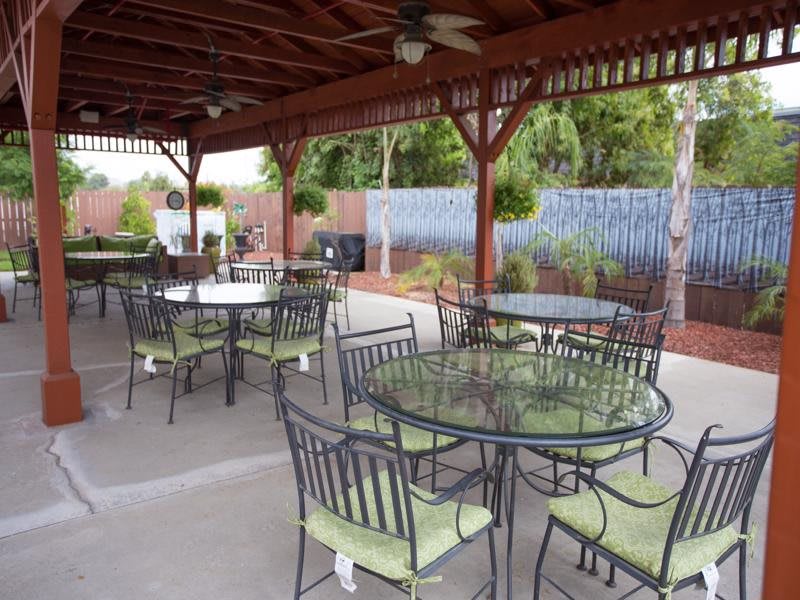 An outdoor patio with multiple tables and chairs under a covered area.
