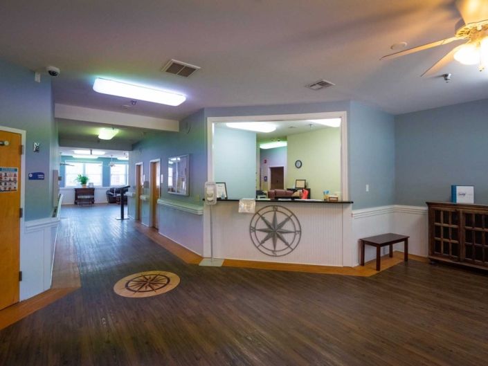 A spacious lobby with a reception area featuring wooden flooring and modern decor.