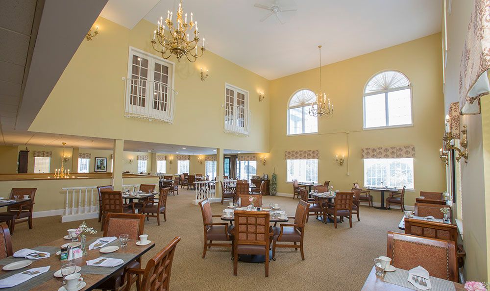 A spacious and elegant dining room with chandeliers, ample seating, and large windows that let in natural light.