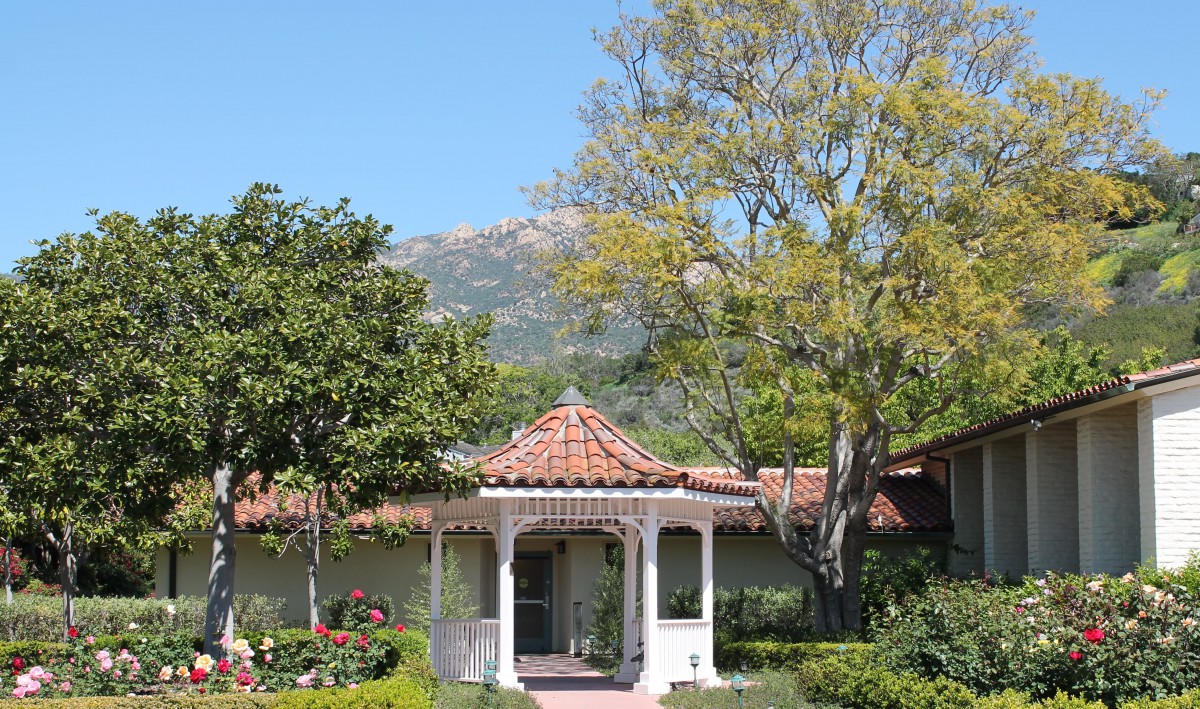 A charming gazebo set amidst lush greenery with a backdrop of mountains.