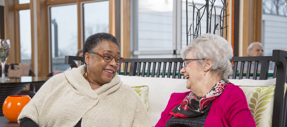 Two women engaged in a joyful conversation indoors.