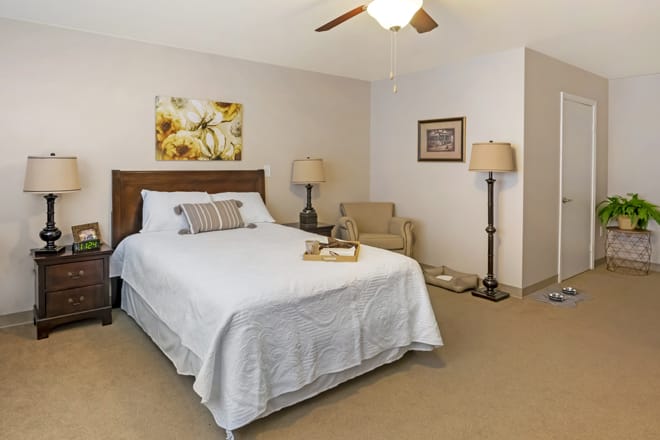 A cozy bedroom with a neatly made bed, two lamps, and tasteful decor.