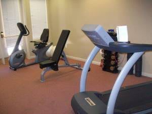 A gym with fitness equipment including a treadmill, exercise bike, and weights.