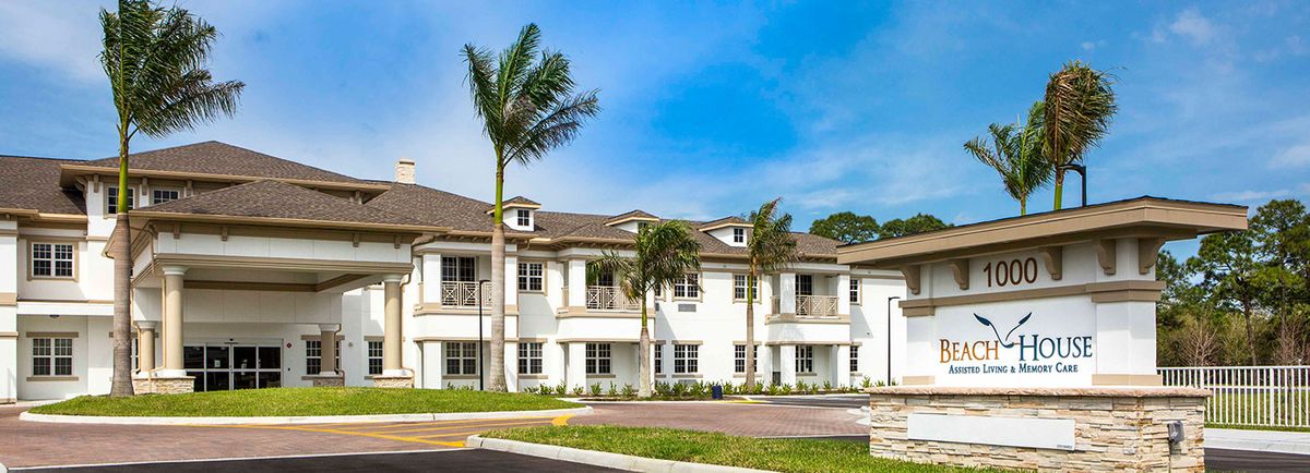 A modern residential townhouse with palm trees in front, showcasing white exterior design.