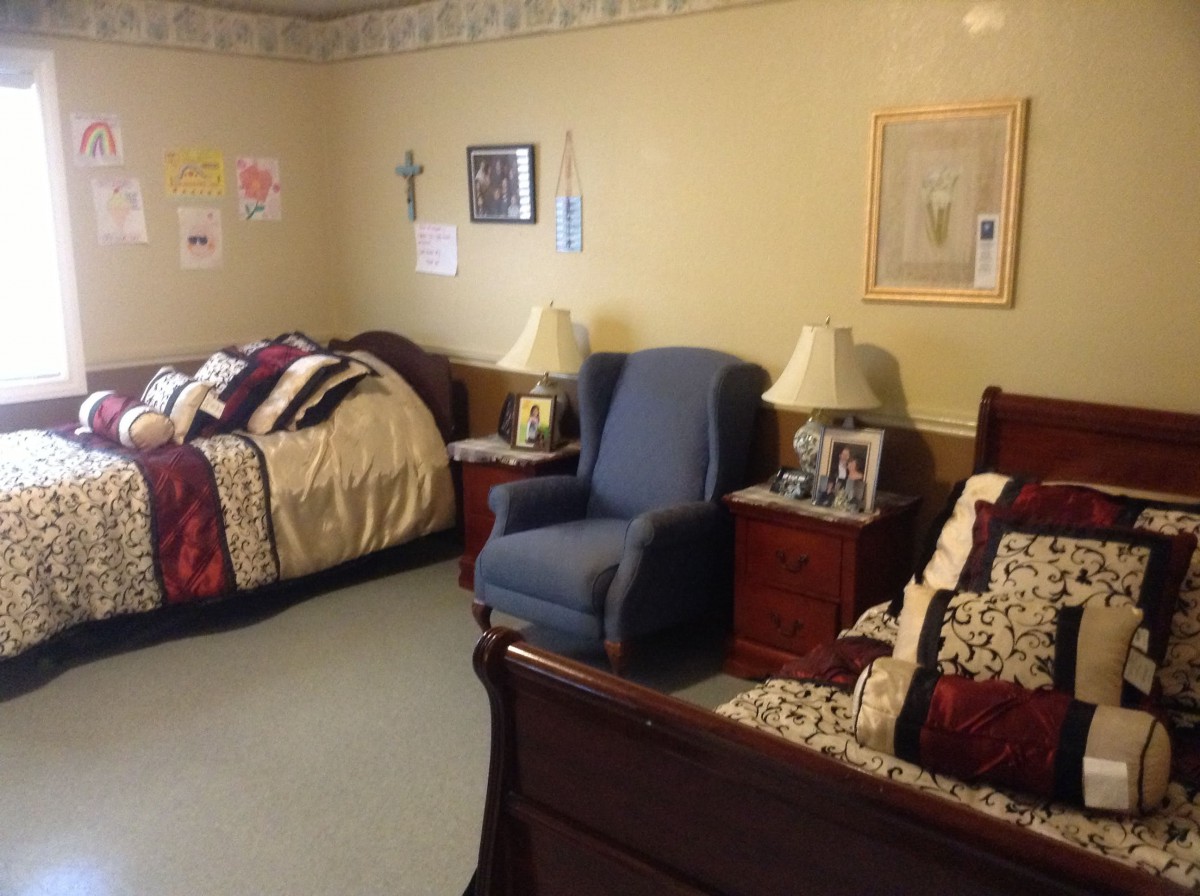 A cozy bedroom with two beds, an armchair, and nightstands with lamps.