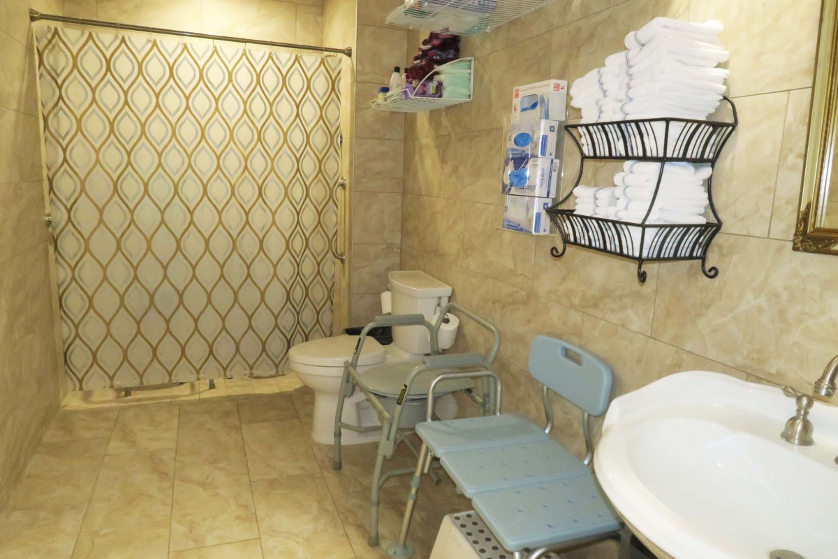 An accessible bathroom with a shower, toilet, and various assistive devices.
