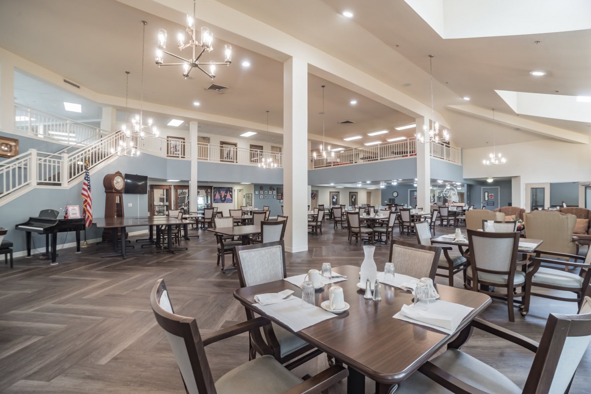 A spacious and elegantly decorated restaurant dining area with tables, chairs, and chandeliers.