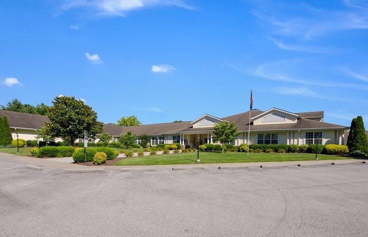 A wide view of a residential building surrounded by trees under a clear blue sky.