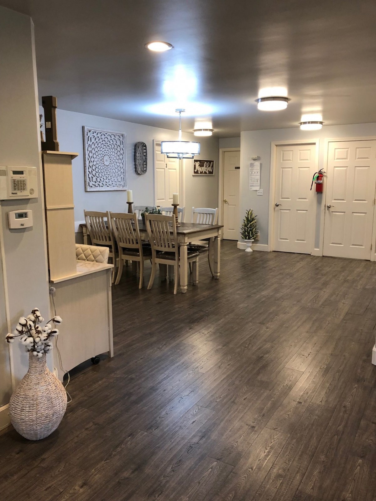 A modern dining area featuring a large table with chairs, stylish lighting, and sleek hardwood flooring.