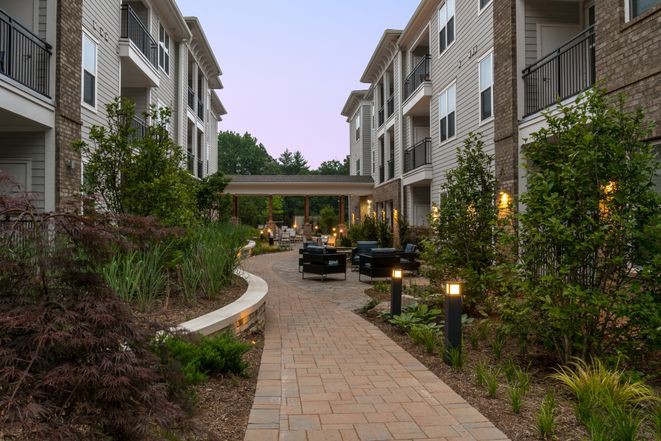 A modern apartment complex with a well-lit pathway and lush landscaping.