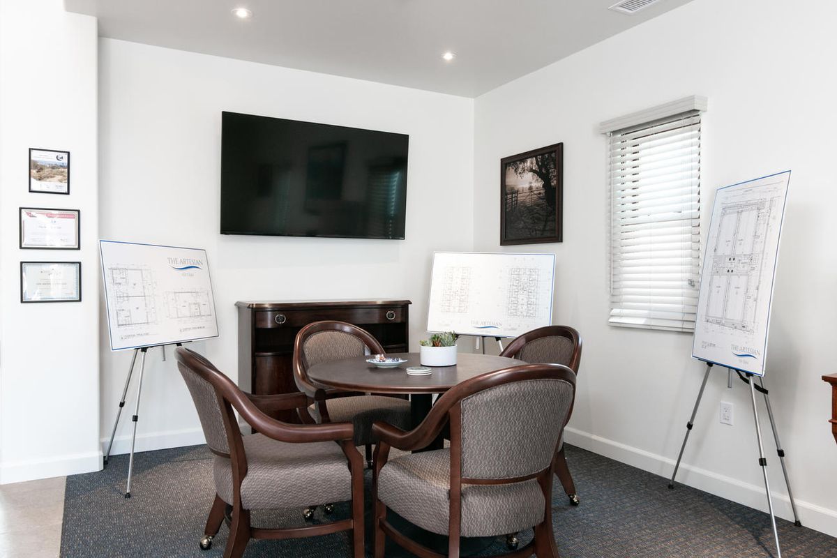 A small meeting room with a conference table and chairs, equipped with a television and whiteboards.