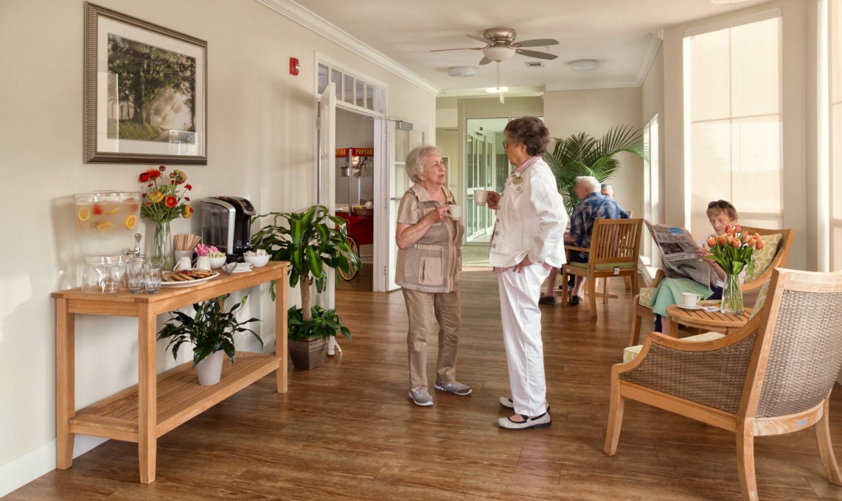 Two elderly people having a conversation in a cozy indoor setting, possibly a retirement home.