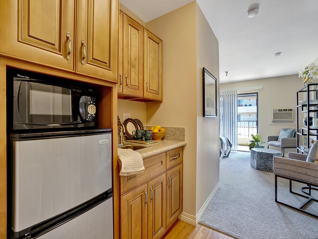 A cozy home interior featuring a kitchen area with wooden cabinets and an open view into the living room.