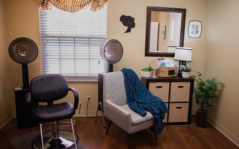 Cozy hair salon interior with a focus on a comfortable seating area, mirror, and hair dryer.
