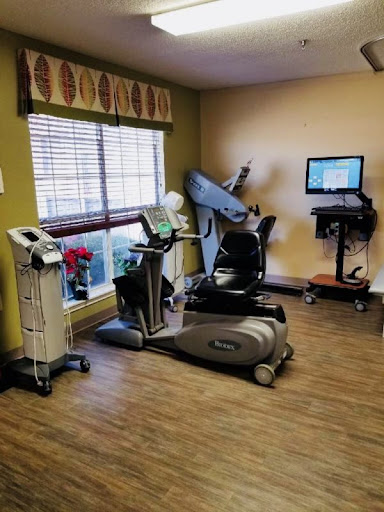 A well-equipped fitness and rehabilitation room featuring various exercise machines and a workstation.