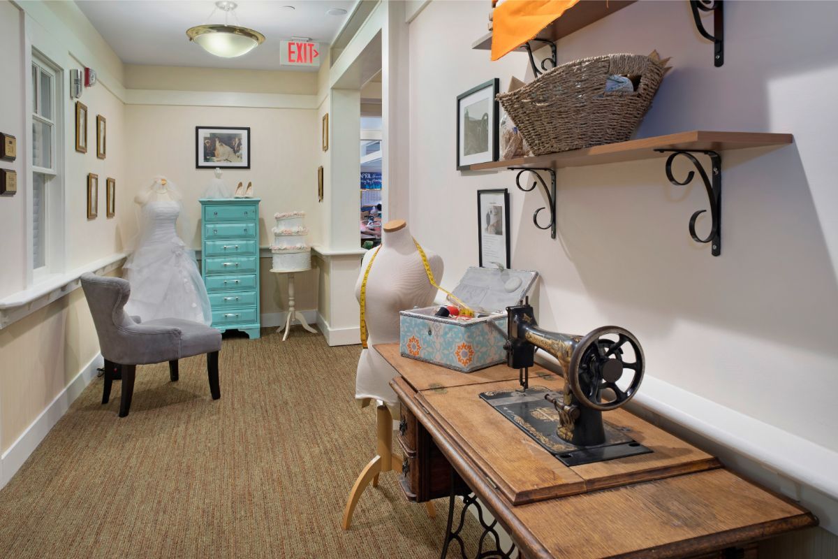 A cozy sewing room featuring a vintage sewing machine and mannequin, with decorative shelving and craft supplies.