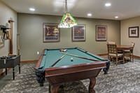 A cozy game room featuring a billiards table under decorative lighting.