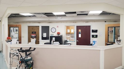 A view of the reception area in a medical office, featuring multiple doors and a clock on the wall.