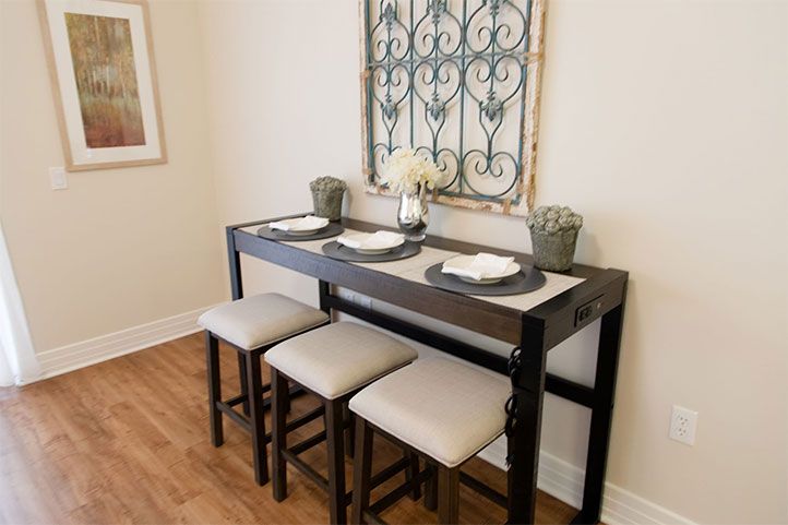 A stylish dining setup featuring a high table with bar stools and elegant wall decor.