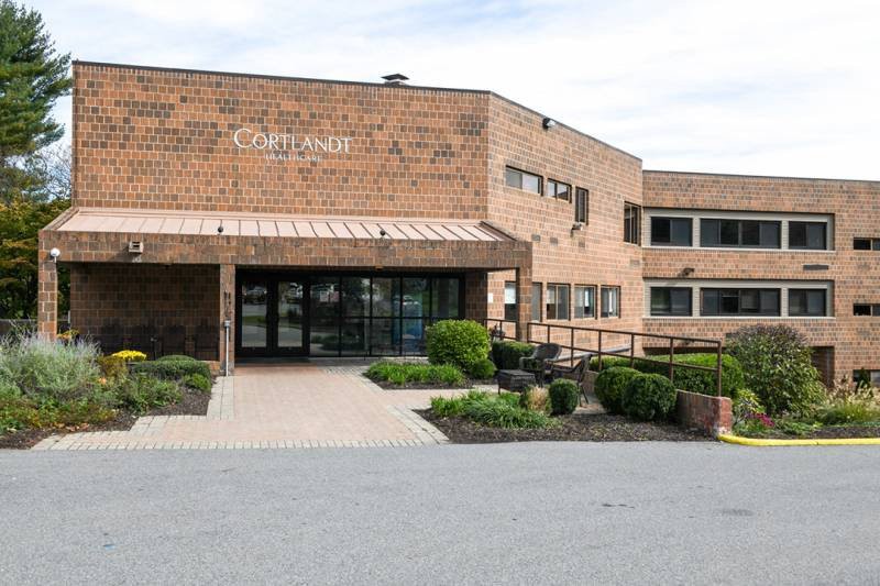 The entrance to a brick healthcare facility with surrounding greenery.